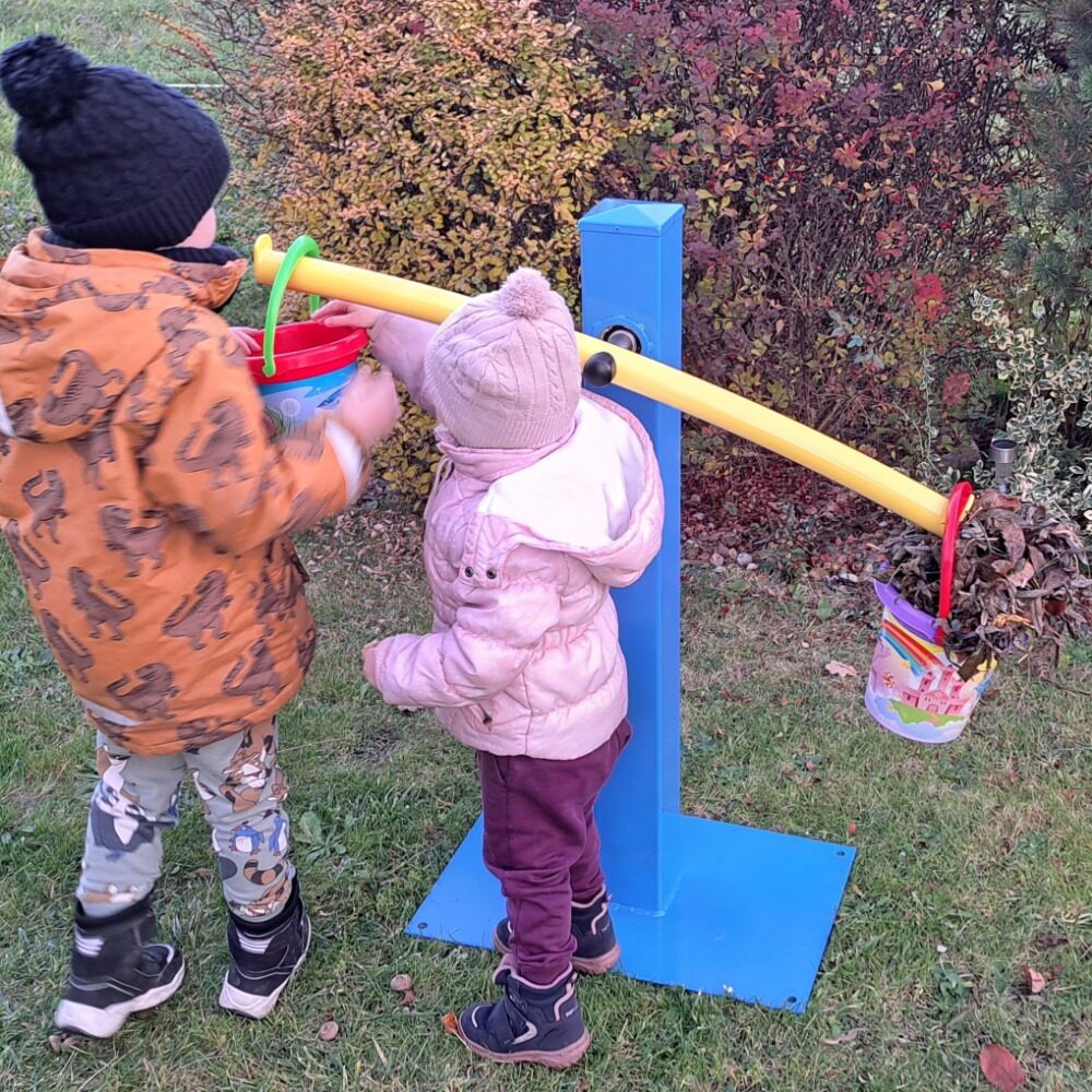 Děti ve školce plní kyblíky na modrožlutých balančních vahách